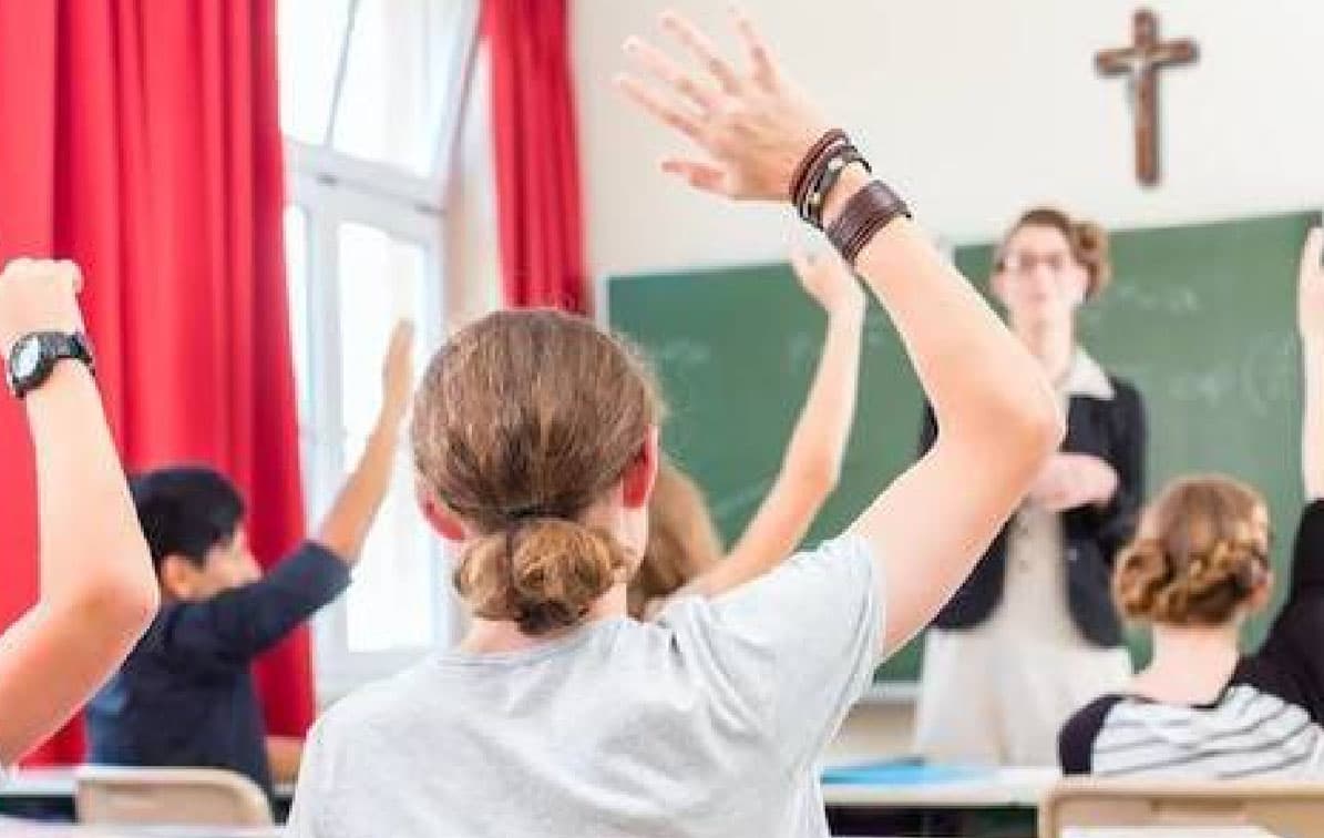 Estudiantes participando en clase de colegio católico